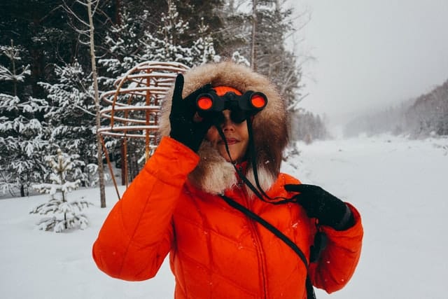 femme utilisant une paire de jumelles noires aux optiques rouges